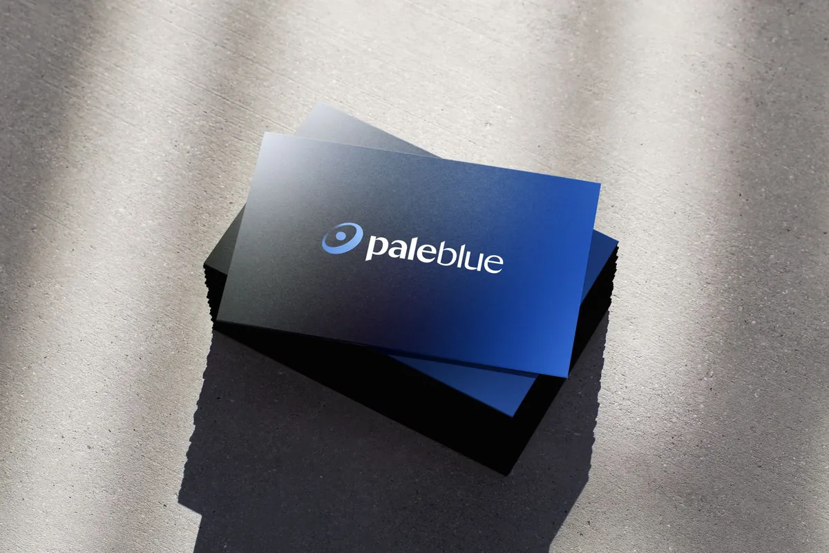 A stack of Pale Blue business cards on concrete: the logo on the dark-to-blue gradient