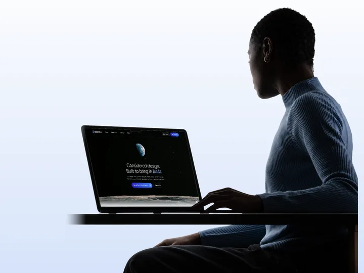 A woman working on a laptop showing the Pale Blue homepage