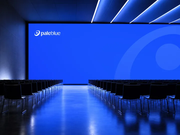 The Pale Blue logo on a large screen in front of rows of seats